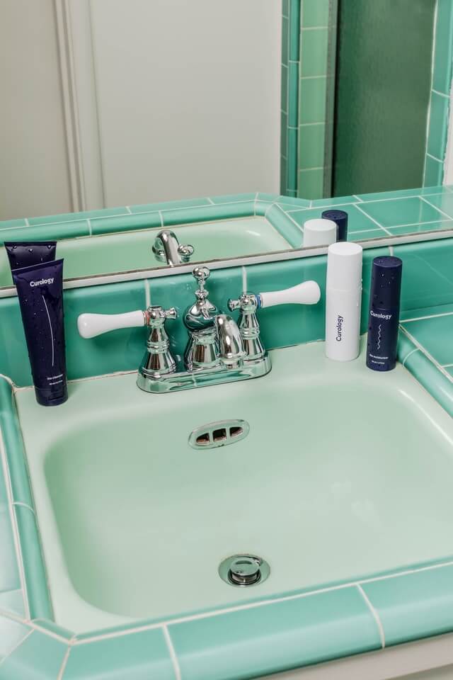 Clean bathroom sink with branded face wash products on the counter