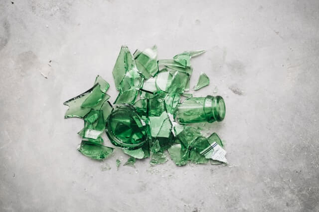 Broken glass bottle. Photo by CHUTTERSNAP on Unsplash.