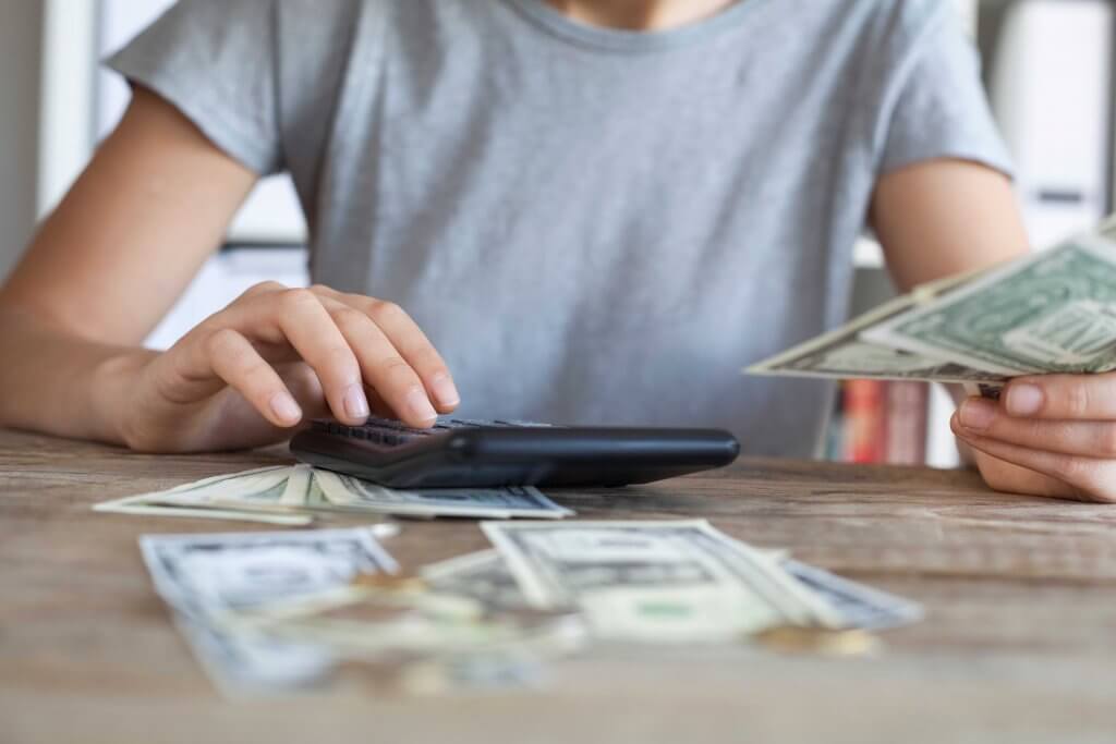 woman using a calculator with money laid out before her