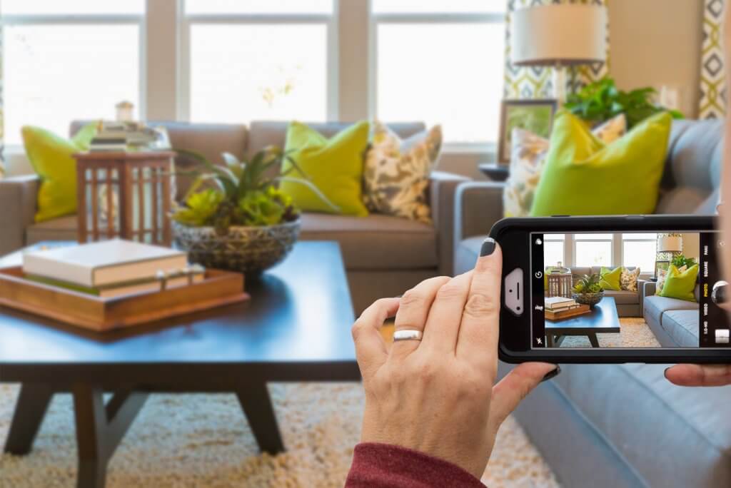 woman taking pictures of her living room couch and coffee table on her phone