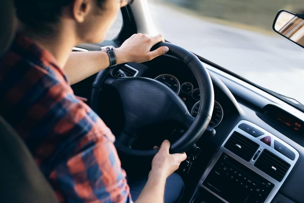 Man driving a vehicle and holding the steering wheel