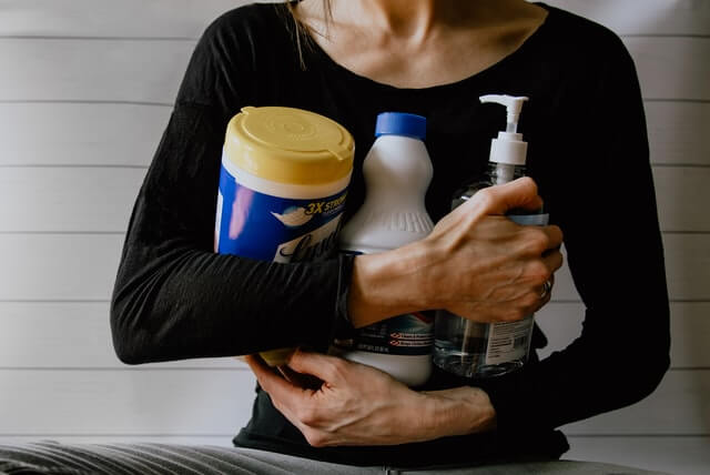 woman holding cleaning supplies 