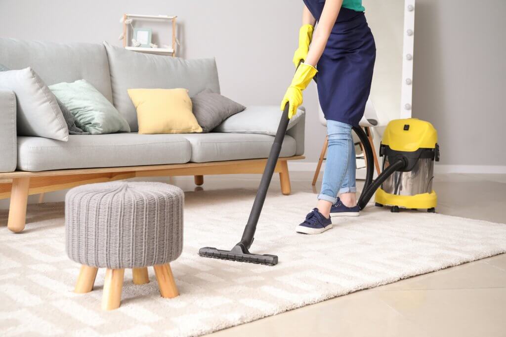 woman vacuuming rug in living room