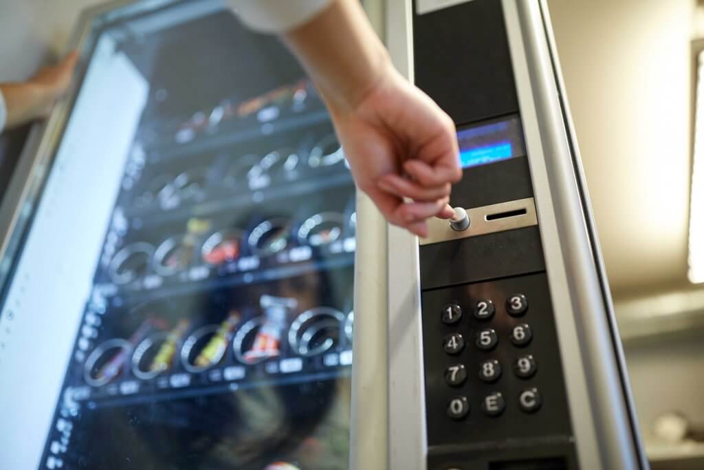 a person is pressing a button on a vending machine.