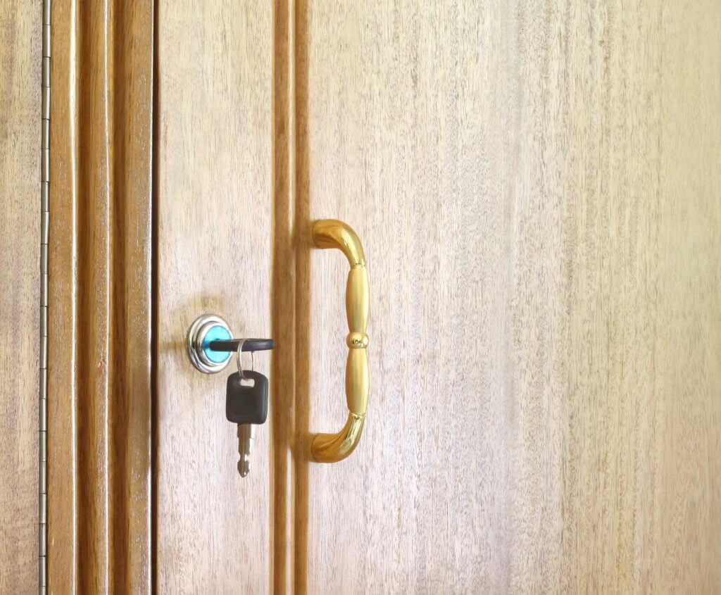 yellow wood door with a gold door handle and house key inserted in the key lock hole