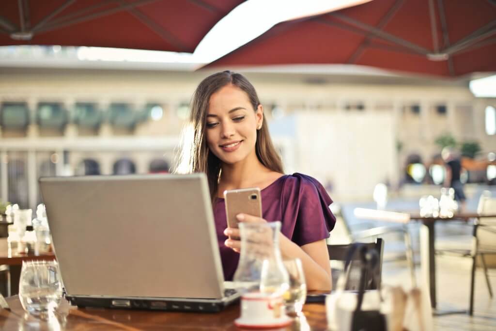woman smiling while looking at phone in an outdoor coffee shop