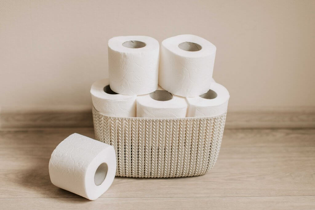 rolls of toilet paper stacked in a small basket 