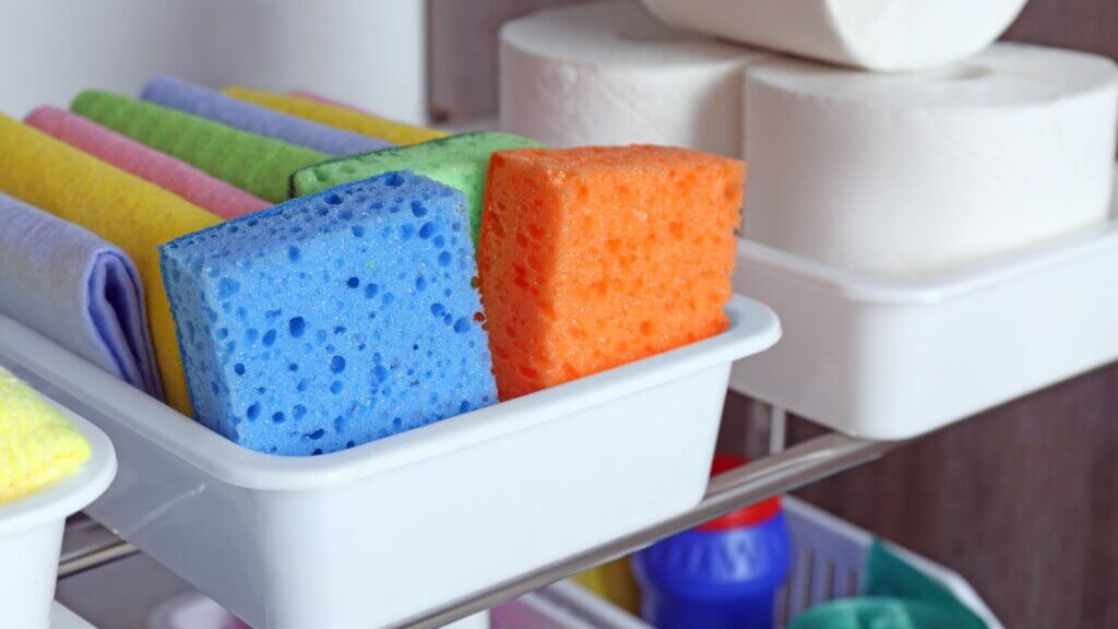 colorful sponges in an organization bin in a utility closet