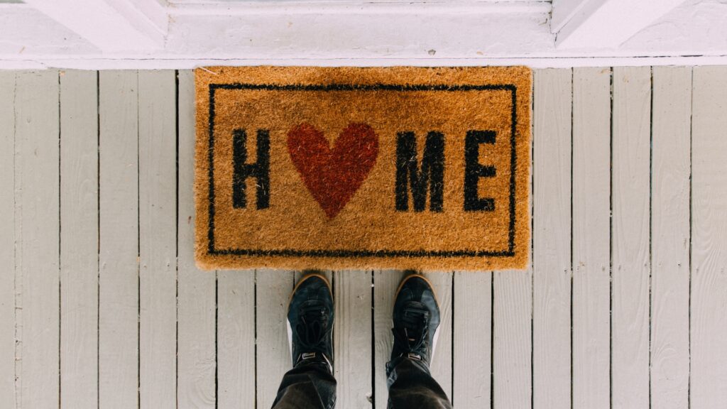 welcome mat at front of door with shoes before it 