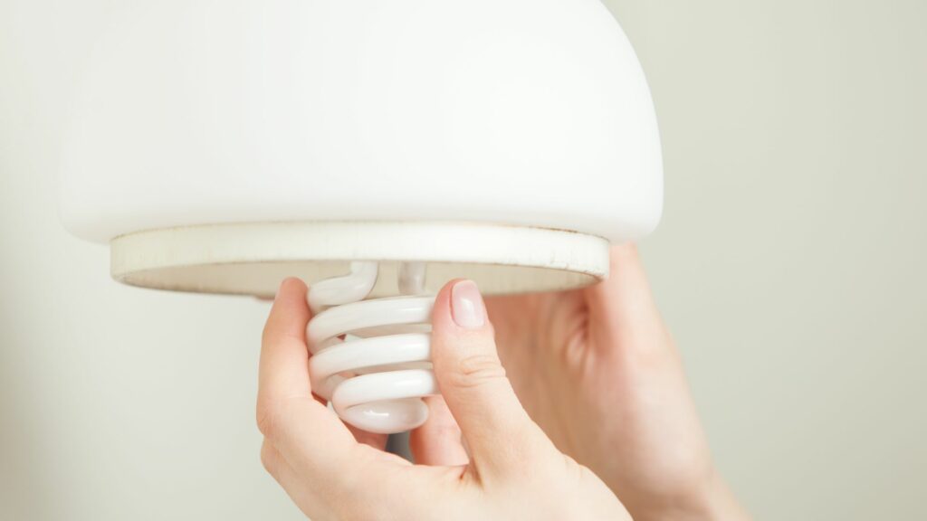 hand screwing in an energy efficient lightbulb